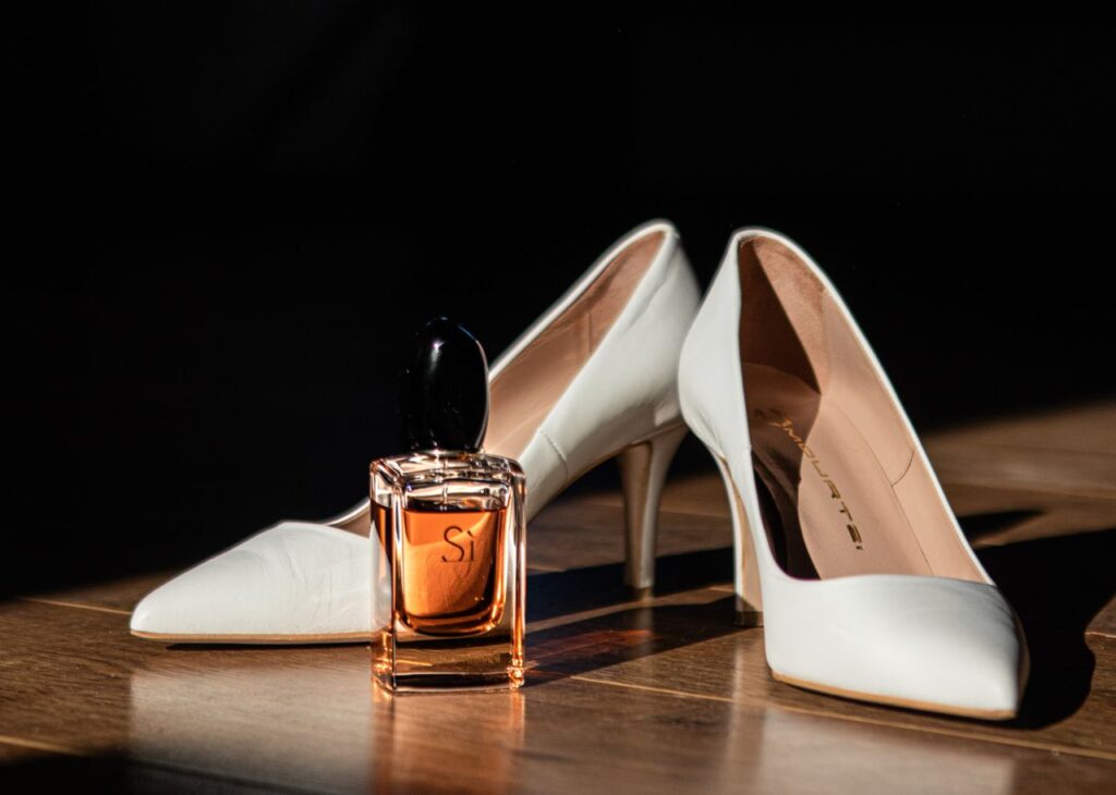 Crafting Captivating Headlines: Your awesome post title goes here Stylish white high heels paired with a luxury perfume bottle on wooden floor.