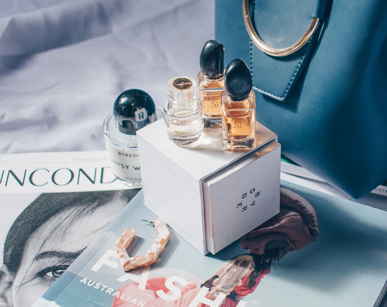 Elegant perfume bottles placed on magazines with a fashion style setting. Perfect for beauty and luxury themes.