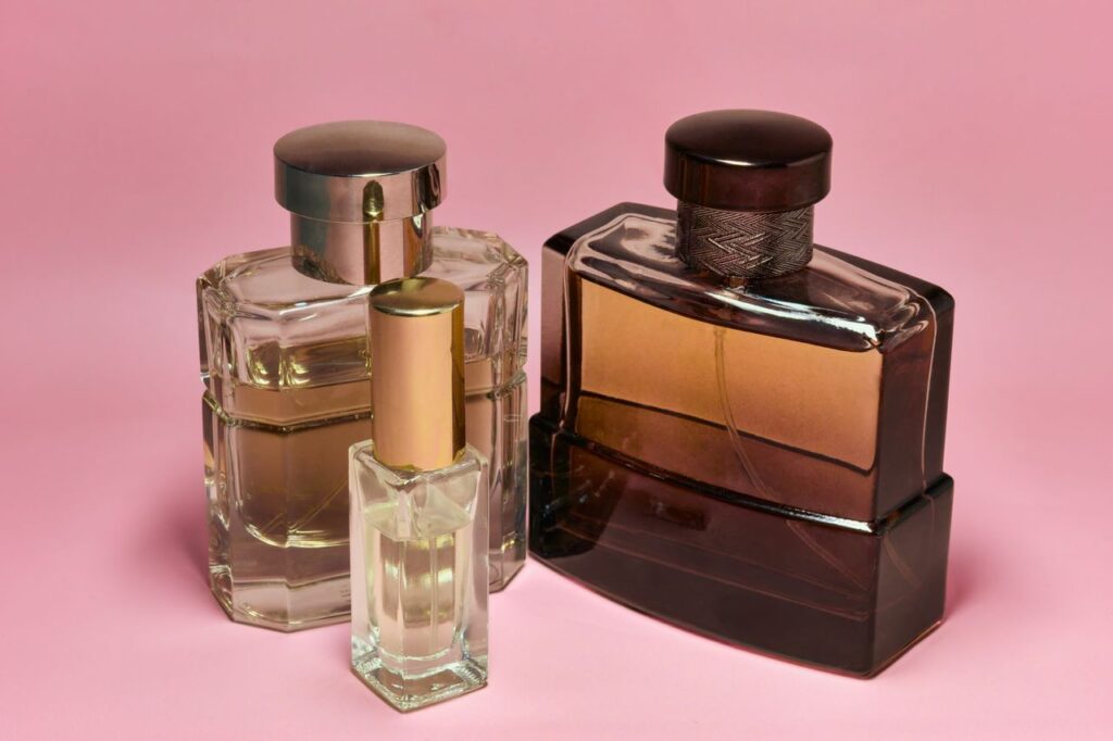 Three stylish perfume bottles with elegant caps on a pink backdrop, capturing a sense of luxury and sophistication.