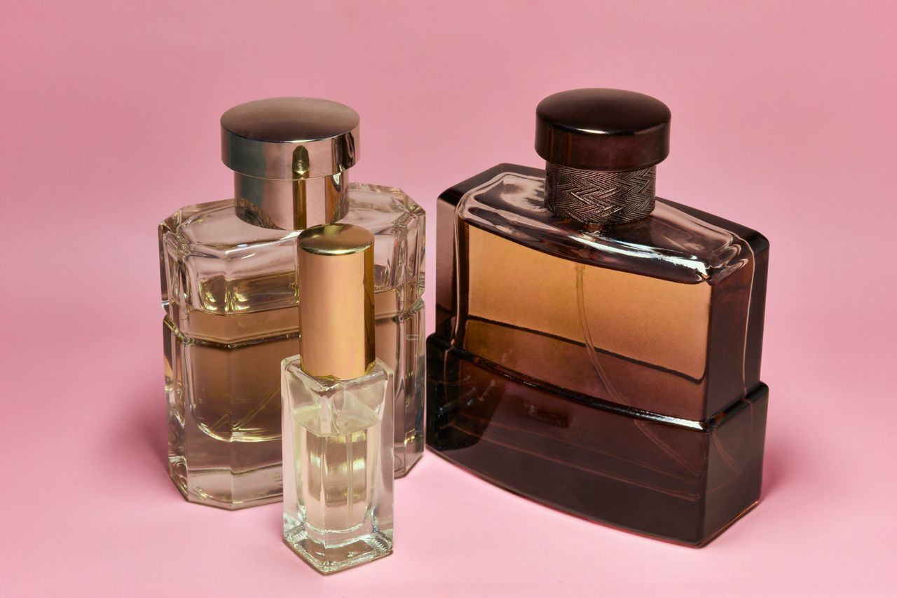 The Art of Drawing Readers In: Your attractive post title goes here Three stylish perfume bottles with elegant caps on a pink backdrop, capturing a sense of luxury and sophistication.